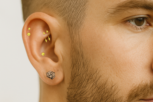 man with gold pvd ear curation featuring a conch piercing and an abstract rose tattoo on his ear lobe