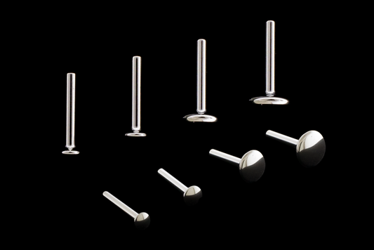 titanium labret posts in a variety of sizes on a black background