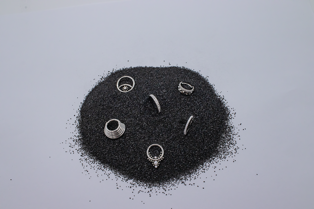 titanium hinged rings arranged in a circle of black sand
