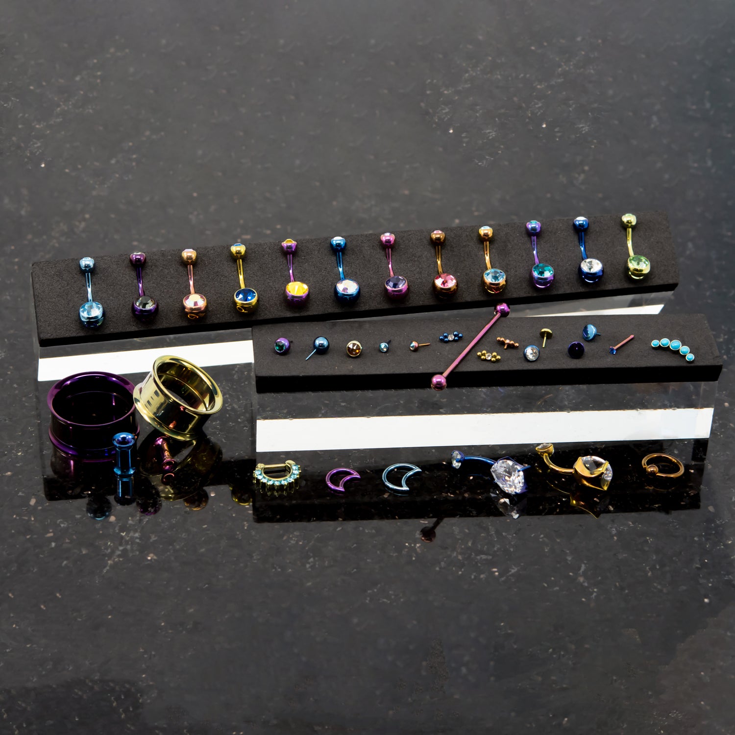 Assorted anodized titanium body jewelry on black marble